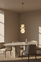 Marble pendant light on a brass pipe glowing above an oval marble dining table