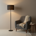 Black Elin floor lamp next to a grey armchair in a warm, minimalist living room
