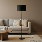 Black Elin floor lamp standing beside a light grey sofa and wooden coffee table