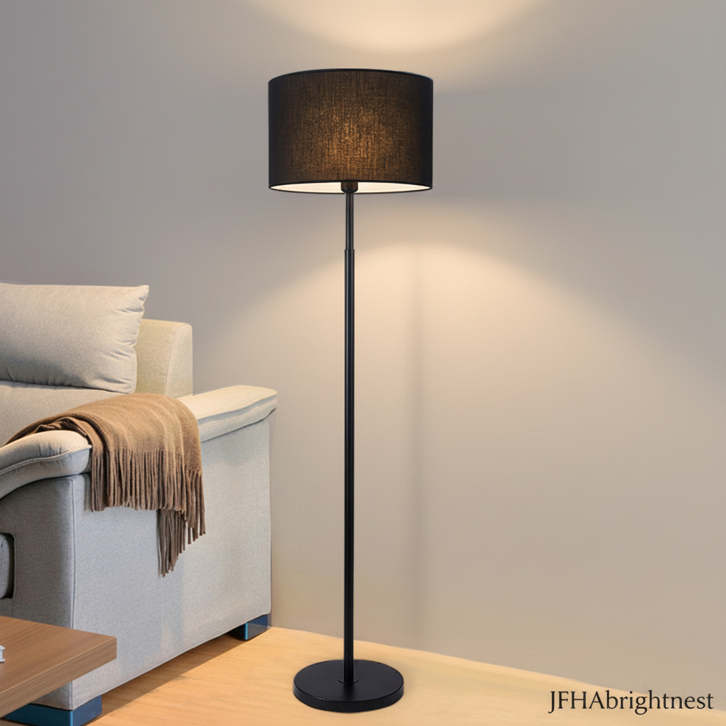 Elin drum shade floor lamp in black with a black fabric shade beside a grey sofa
