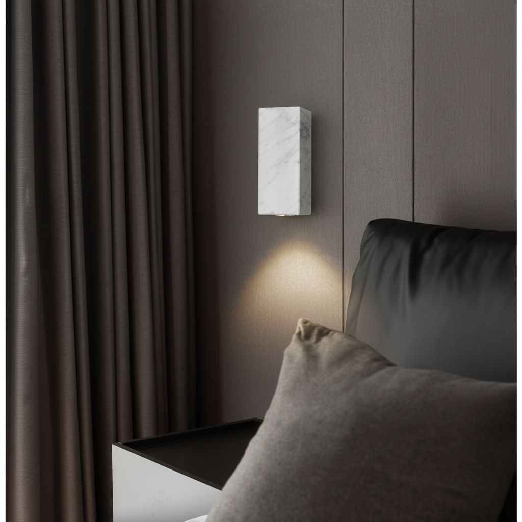 Square white marble wall light glowing warm above a bedside table in a dark modern bedroom