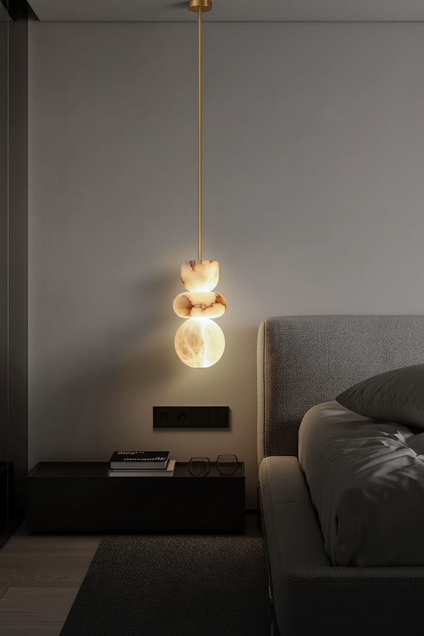 Marble pendant light on a brass pipe beside a bed in a dark, moody bedroom