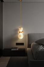 Marble pendant light on a brass pipe beside a bed in a dark, moody bedroom