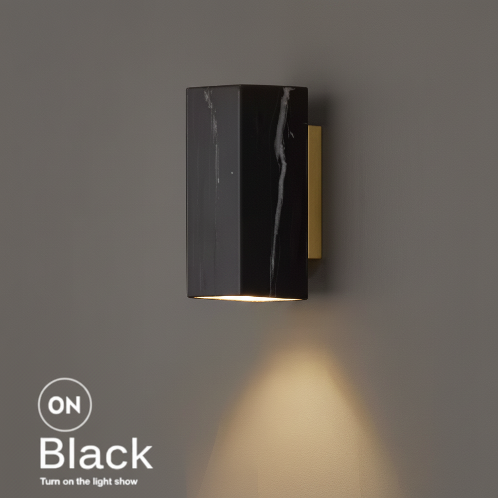 Marble bedside wall light, square black marble shade on a brass bracket, lit with a warm downward glow