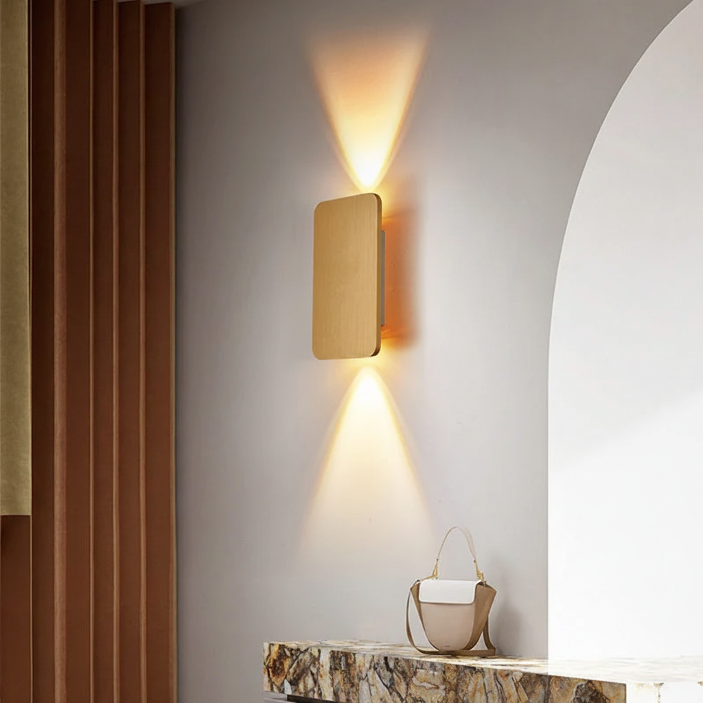 Ingram up-down wall light in gold, lit on an interior wall