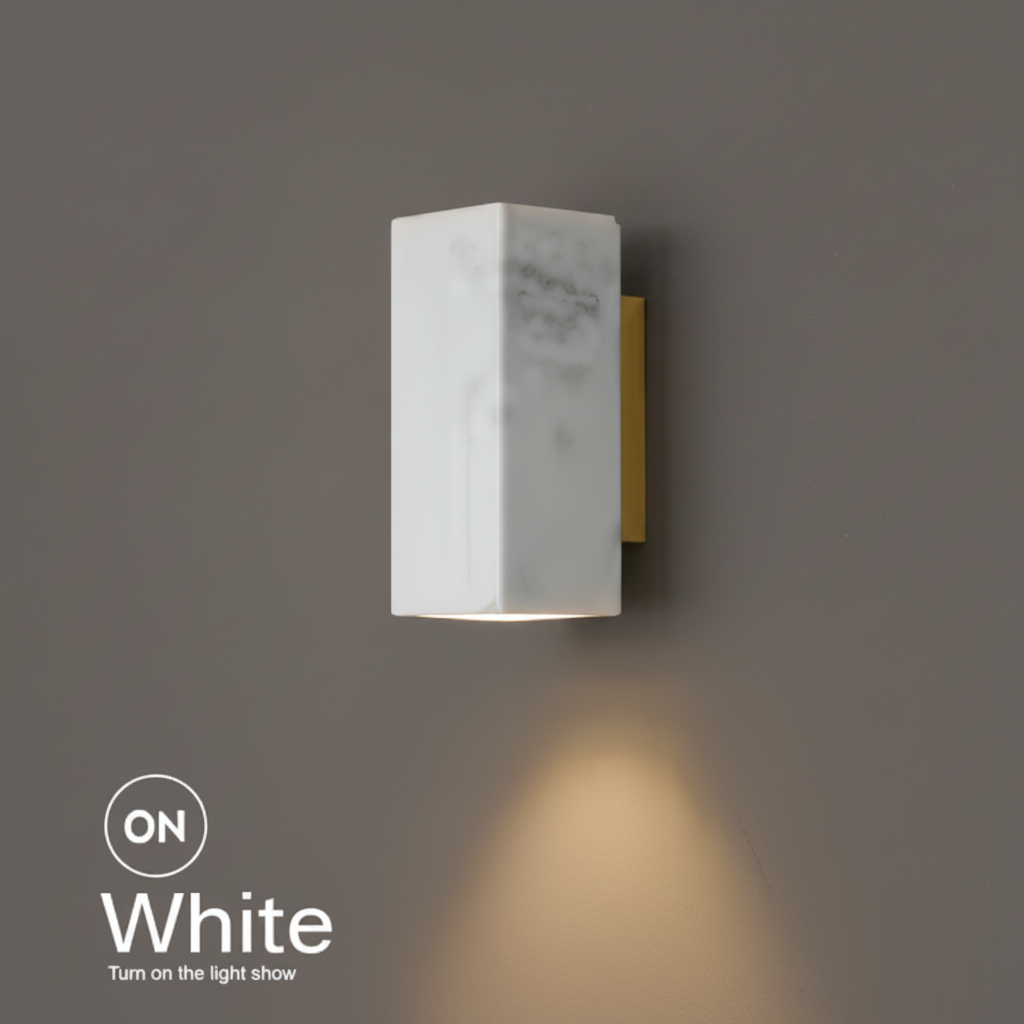 Marble bedside wall light, square white marble shade on a brass bracket, lit with a warm downward glow