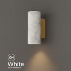 Marble bedside wall light, round white marble shade on a brass bracket, lit with a warm downward glow