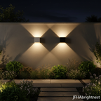 White and black Norvik outdoor wall lights in a garden at dusk