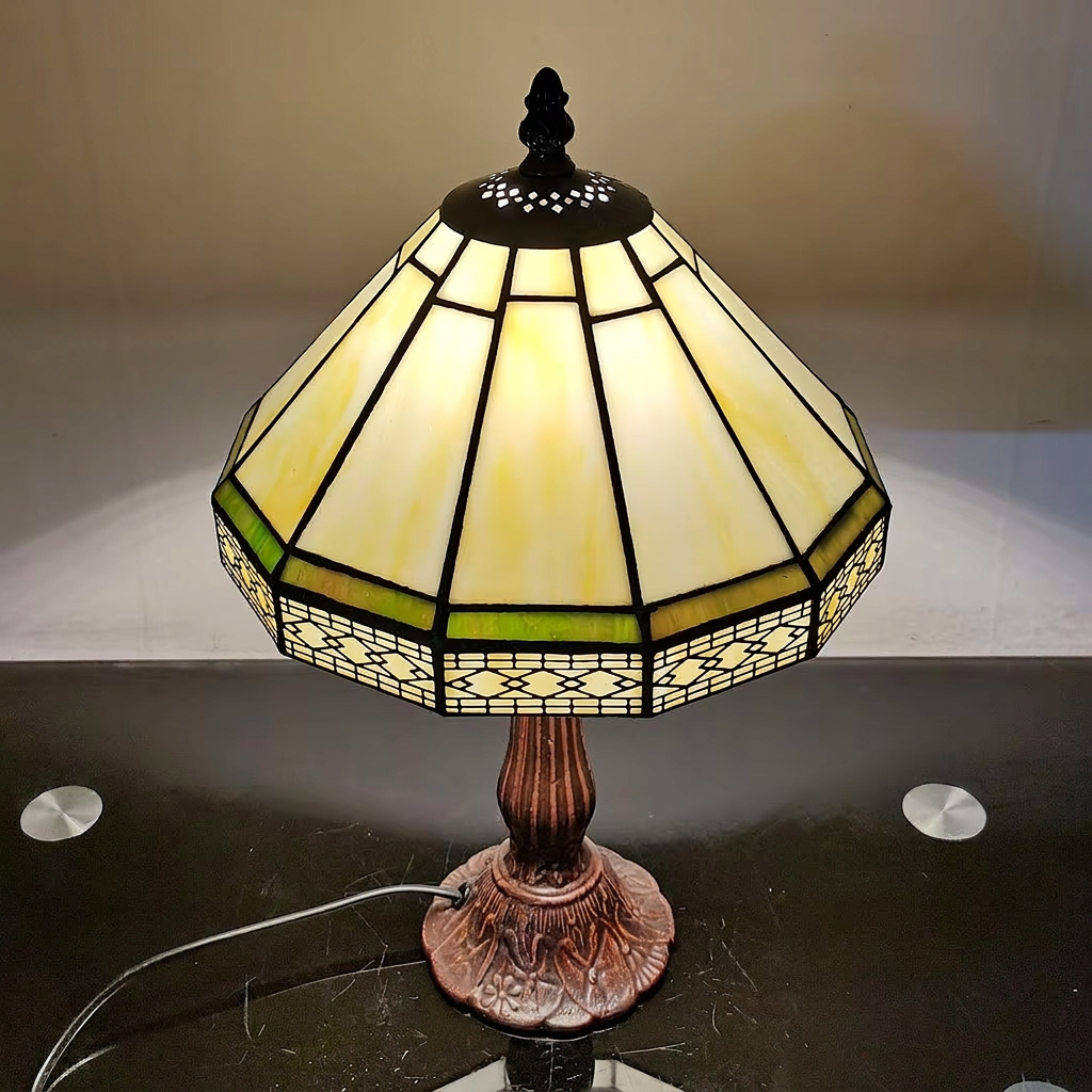Geometric Tiffany lamp switched on, showing the cream glass panels and green accent stripe