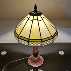 Geometric Tiffany lamp switched on, showing the cream glass panels and green accent stripe
