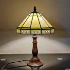 Lit cream stained glass table lamp casting a warm glow on the wall