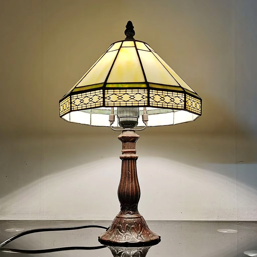 Low-angle view of the lit Tiffany lamp showing the lace-pattern border and E27 bulb holder