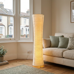 Rice paper floor lamp glowing beside a sofa in a UK bay-window living room