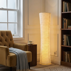 Rice paper column floor lamp lighting a reading nook with armchair and bookshelves