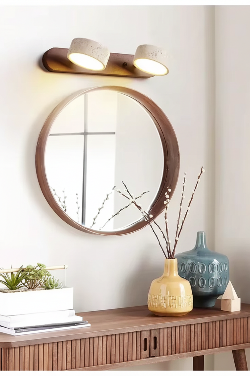 Walnut 2-light wall light above a round mirror and wooden sideboard